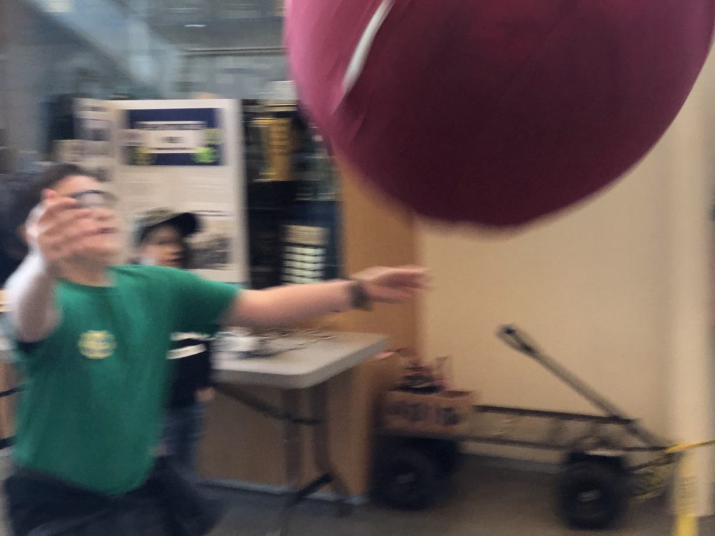 A young student launches the ball with ATLaS as another student catches it!